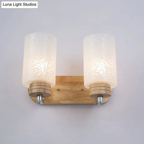 Modern 2-Headed White Glass Cylinder Wall Sconce With Wood Mount And Rose Pattern